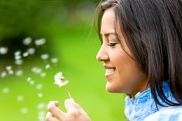 beautiful woman blowing a flower and smiling
