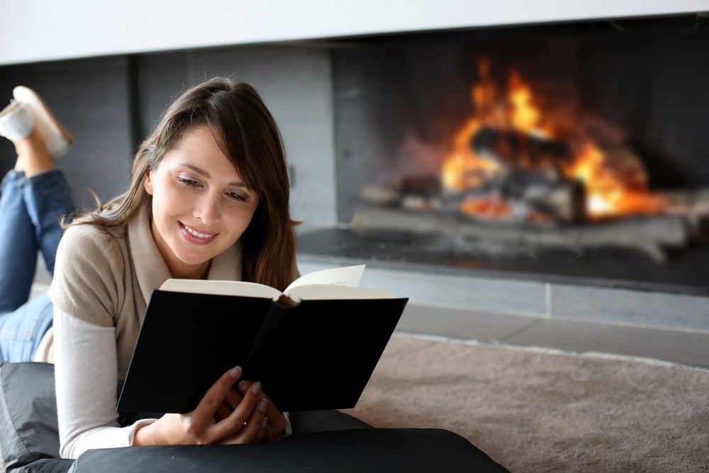Portrait of beautiful woman reading book by fireplace.jpeg